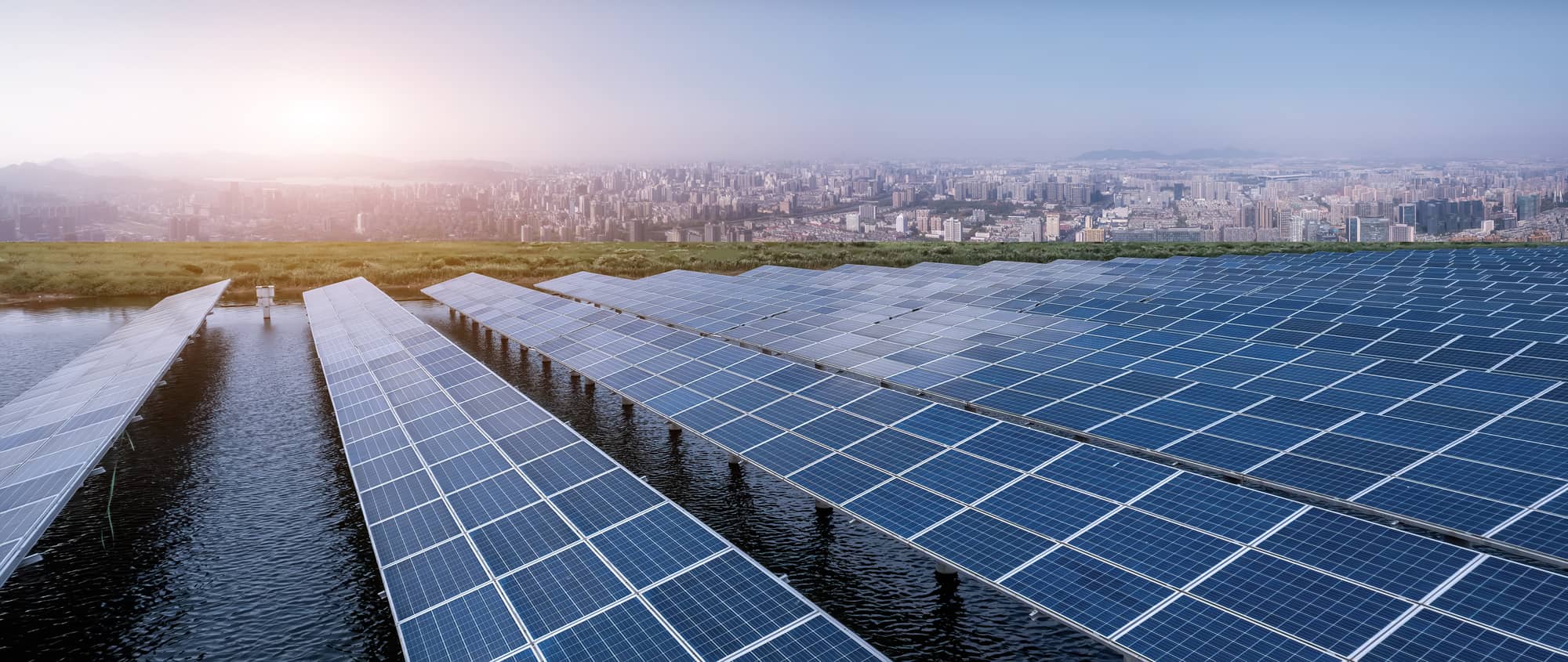 Centrales photovoltaïques installées sur un plan d'eau avec une ville en arrière-plan.